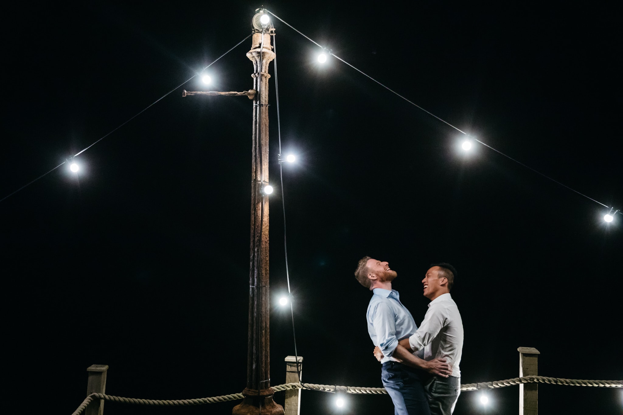 Same sex couple at the end of their wedding under festoon lighting